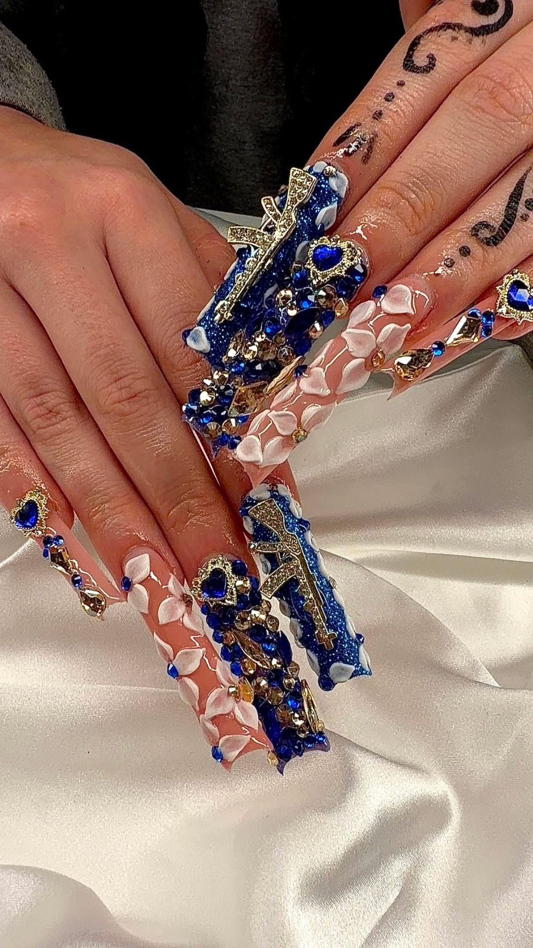 Beyond xtra long blue rhinestone Gel-X set with gold cross charms and 3D white florals